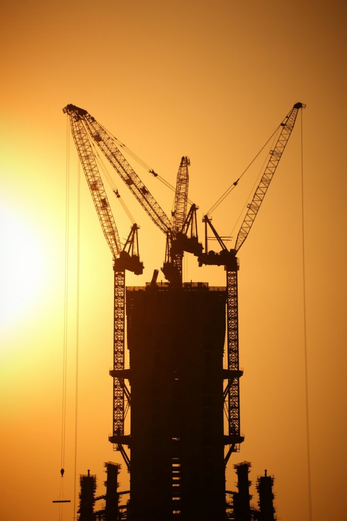 construction of a skyscraper by cranes at sunset